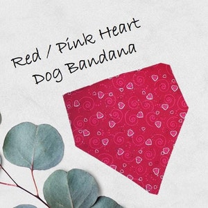 May include: Red dog bandana with a pink heart and swirl pattern. The text "Red / Pink Heart Dog Bandana" is written above the bandana.