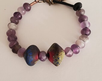 Purple bracelet with 2 lampwork glass beads in the center.  Strung on leather as there with a leather loop and clasp