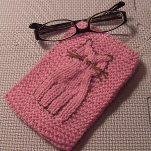 May include: A pink knitted glasses case with a brown embroidered cat design.