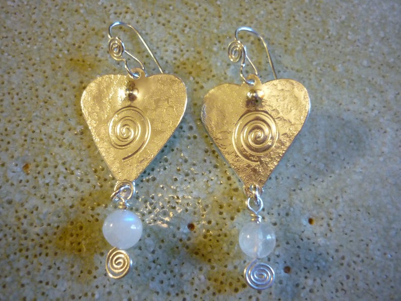 Puede incluir: Pendientes de plata en forma de coraz&oacute;n con un dise&ntilde;o en espiral y un colgante de cuentas blancas.