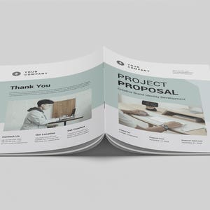 May include: Open brochure with the text "PROJECT PROPOSAL" and "Thank You". The brochure has a light blue and white design. The brochure includes images of people working on computers.
