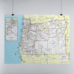May include: A vintage map of Oregon, printed in yellow and green, with county borders outlined in black. The map includes a smaller inset map of the Portland area. The text "Oregon 163" appears in the bottom right corner.