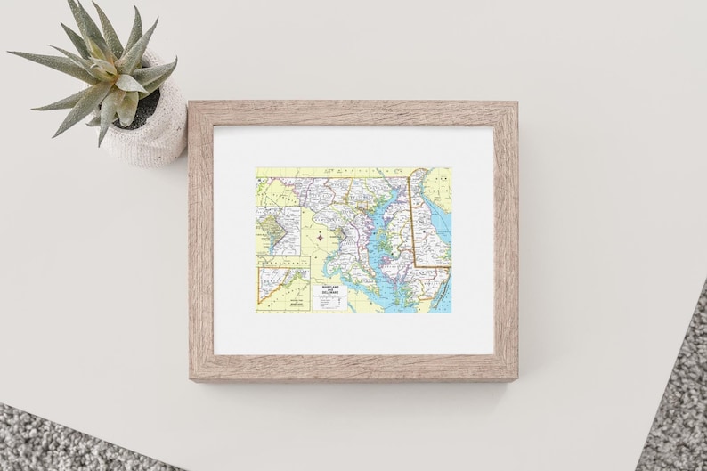 May include: A framed map of Maryland with a light brown frame. The map is in a vintage style and shows the state's major cities, roads, and waterways.