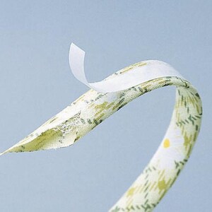May include: A white fabric tape with adhesive backing, partially peeled back to reveal the adhesive. The fabric has a floral pattern in shades of green and yellow.