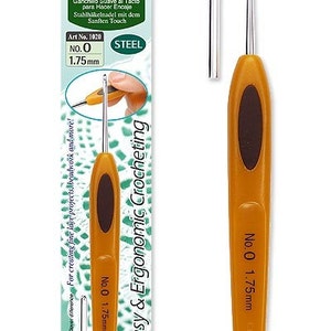 May include: A close-up of a Clover Soft Touch Steel Crochet Hook in size 0 (1.75 mm). The hook is orange and brown with a silver hook. The packaging shows the hook in use and includes the text "Easy & Ergonomic Crocheting".