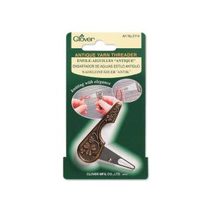 May include: A Clover Antique Yarn Threader on a green and white card. The threader is bronze-colored with a floral design and a small blade. The card includes the text "ANTIQUE YARN THREADER" and "knitting with elegance."