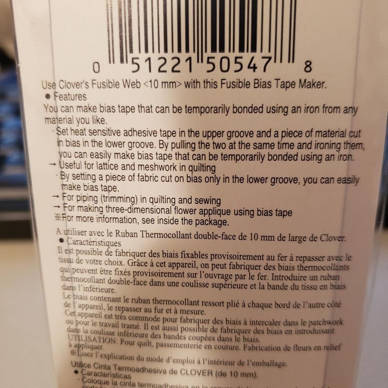 May include: Close-up of a white and black package with a barcode and product information. The package is for a Clover Fusible Bias Tape Maker. The text on the package reads: "Use Clover's Fusible Web <10 mm> with this Fusible Bias Tape Maker."
