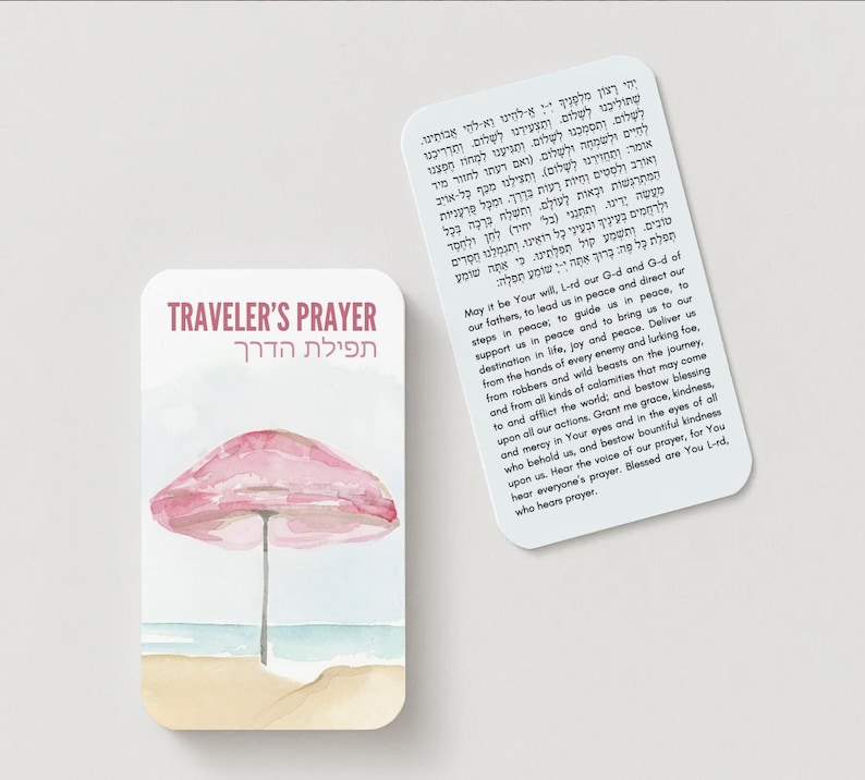 K&ouml;nnte beinhalten: Eine Karte im Aquarellstil mit dem Text "TRAVELER'S PRAYER" und hebr&auml;ischen Text. Die Karte zeigt einen rosa Sonnenschirm an einem Sandstrand mit blauem Ozean. Eine zweite Karte mit Text ist ebenfalls vorhanden.