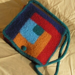 May include: A teal blue crocheted bag with a geometric pattern in shades of red, orange, blue, and green.