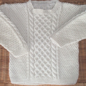 Hand knit child&#39;s sweater in a white Scandinavian cable knit design