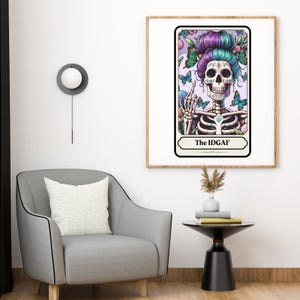 Puede incluir: Una impresi&oacute;n art&iacute;stica enmarcada que presenta un esqueleto estilizado con un tocado floral y mariposas. El esqueleto levanta un dedo. El texto "The IDGAF" est&aacute; en la parte inferior de la impresi&oacute;n. La impresi&oacute;n est&aacute; en un marco de madera.