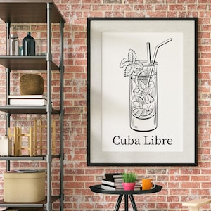 May include: Black and white framed print featuring a Cuba Libre cocktail illustration. The drink is in a tall glass with ice, mint, and a straw. The words "Cuba Libre" are printed below the image.