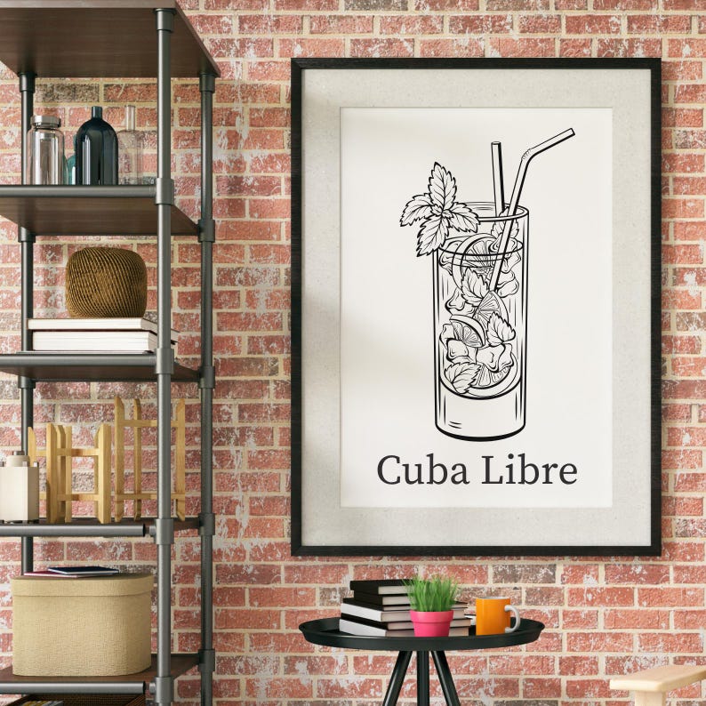 May include: Black and white framed print featuring a Cuba Libre cocktail illustration. The drink is in a tall glass with ice, mint, and a straw. The words "Cuba Libre" are printed below the image.