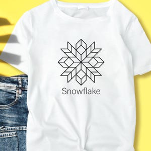 May include: White t-shirt featuring a black geometric snowflake design. The word "Snowflake" is printed below the graphic. The shirt is made of a soft material and is suitable for casual wear.