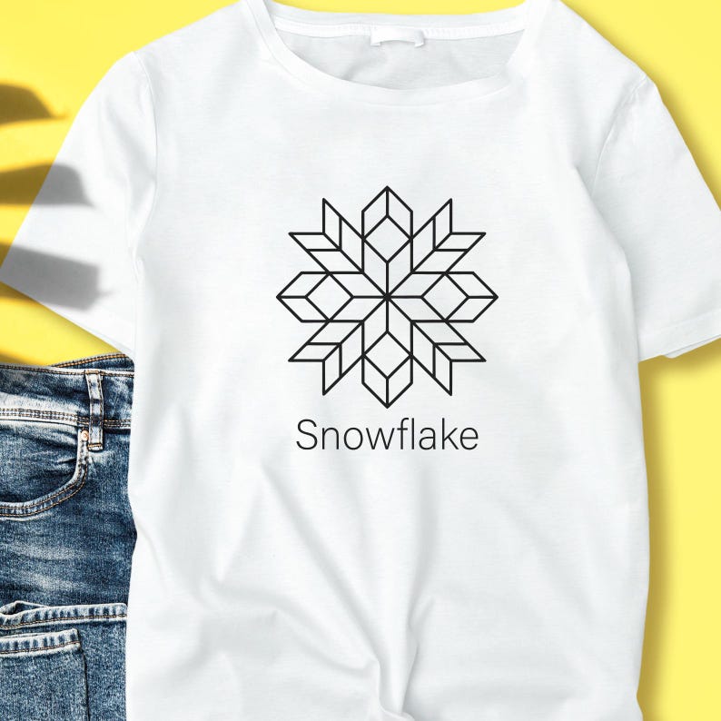 May include: White t-shirt featuring a black geometric snowflake design. The word "Snowflake" is printed below the graphic. The shirt is made of a soft material and is suitable for casual wear.
