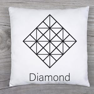 May include: White square pillow with a black geometric diamond design. The word "Diamond" is printed in black below the design. The pillow is on a wooden surface.