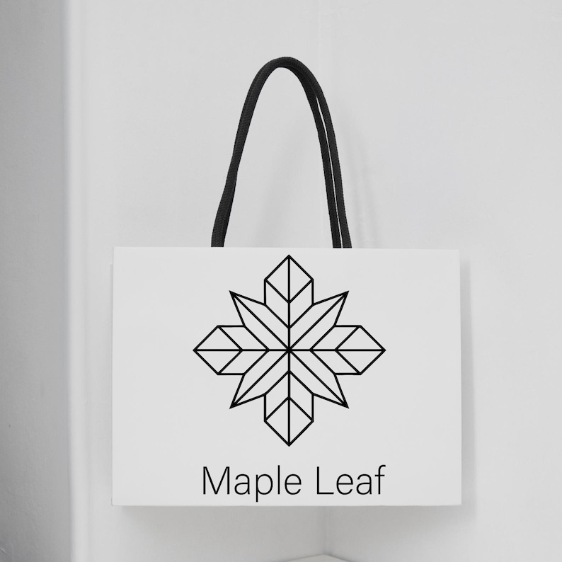 May include: White shopping bag with a black geometric maple leaf design and the words "Maple Leaf" in a simple font. The bag has a black rope handle.