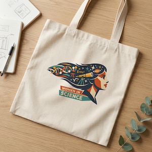Puede incluir: Bolso tote de color crema con un gráfico del perfil de una mujer. El diseño incorpora símbolos científicos y el texto "WOMEN IN SCIENCE". El cabello de la mujer incluye hebras de ADN, símbolos matemáticos y un telescopio.