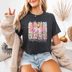 Puede incluir: Una camiseta gris oscuro con una ilustraci&oacute;n colorida de Jesucristo y el texto "Every knee shall bow Philippians 2:10-11".