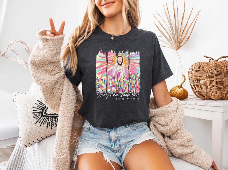 Puede incluir: Una camiseta gris oscuro con una ilustraci&oacute;n colorida de Jesucristo y el texto "Every knee shall bow Philippians 2:10-11".