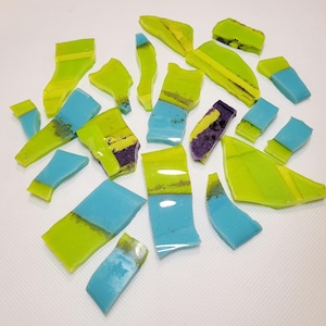 Könnte beinhalten: Sortiment aus zerbrochenen Glassplittern in Grün-, Blau- und Violetttönen. Das Glas hat eine marmorierte, geschichtete Optik.