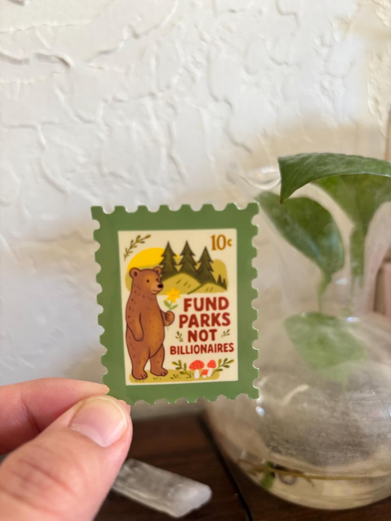 K&ouml;nnte beinhalten: Eine gr&uuml;ne Briefmarke mit einem braunen B&auml;ren, der eine Blume h&auml;lt, mit dem Text "Fund Parks Not Billionaires". Die Briefmarke zeigt auch eine gelbe Sonne, gr&uuml;ne B&auml;ume und rote Pilze. Die Briefmarke ist 10 Cent wert.
