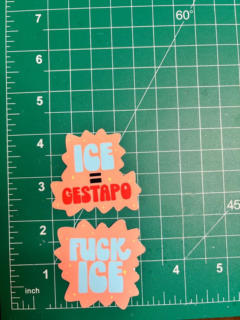 Puede incluir: Dos pegatinas con fondo melocot&oacute;n y texto azul y rojo. Una pegatina dice "ICE = GESTAPO" y la otra "FUCK ICE". Las pegatinas est&aacute;n sobre una esterilla de corte verde con medidas en pulgadas, equivalentes a 2,54 cm.