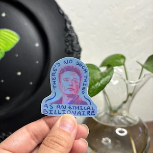 Könnte beinhalten: Ein blauer und weißer Aufkleber mit einer Zeichnung von Elon Musk und dem Text "Es gibt keinen ethischen Milliardär".