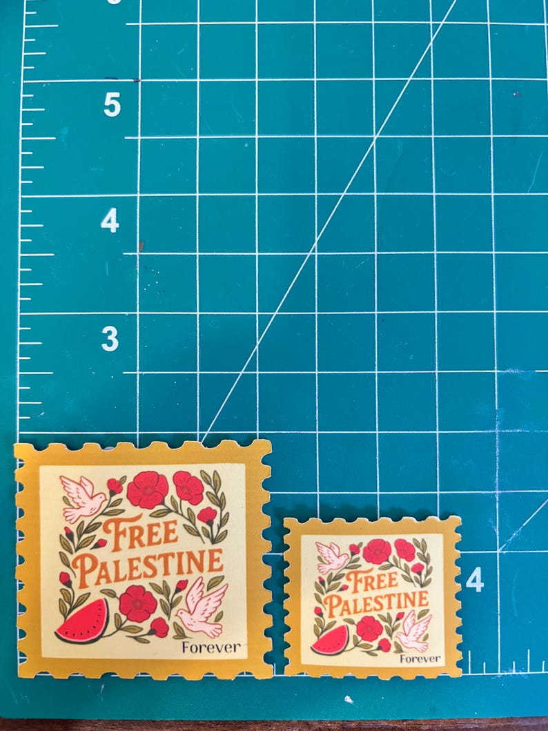 May include: Two postage stamps with a yellow border and a cream-colored center. The stamps feature the text "Free Palestine" with illustrations of doves, flowers, and a watermelon. The word "Forever" is printed at the bottom of each stamp.