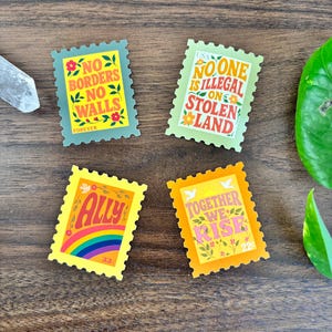 a set of four stamp-shaped stickers. one sticker reads “no borders no walls.” Another sticker reads “no one is illegal on stolen land.” Another sticker reads “together we rise.” and the last one reads “ally” featuring a rainbow and a dove.