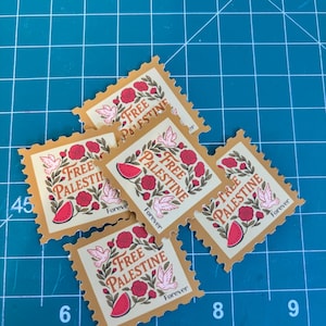 May include: A collection of postage stamp-style stickers with a tan border and a design featuring the words "Free Palestine", a watermelon slice, flowers, and doves. The word "Forever" is also printed on the stickers.