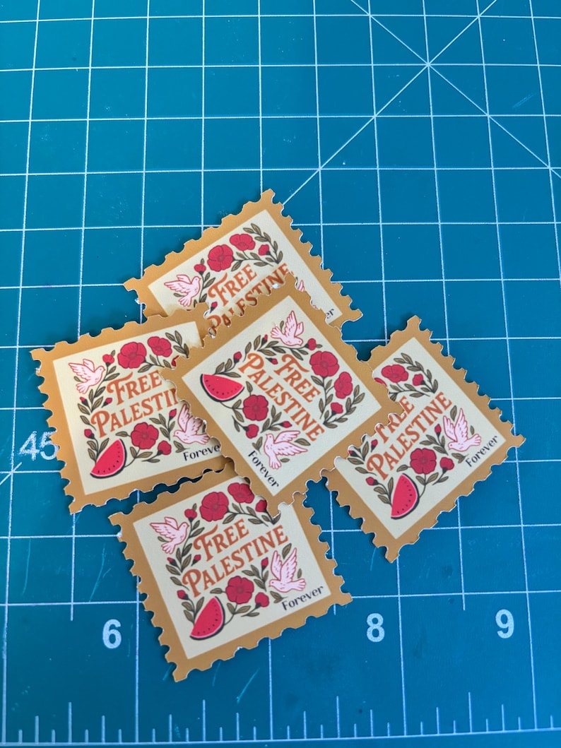 May include: A collection of postage stamp-style stickers with a tan border and a design featuring the words "Free Palestine", a watermelon slice, flowers, and doves. The word "Forever" is also printed on the stickers.