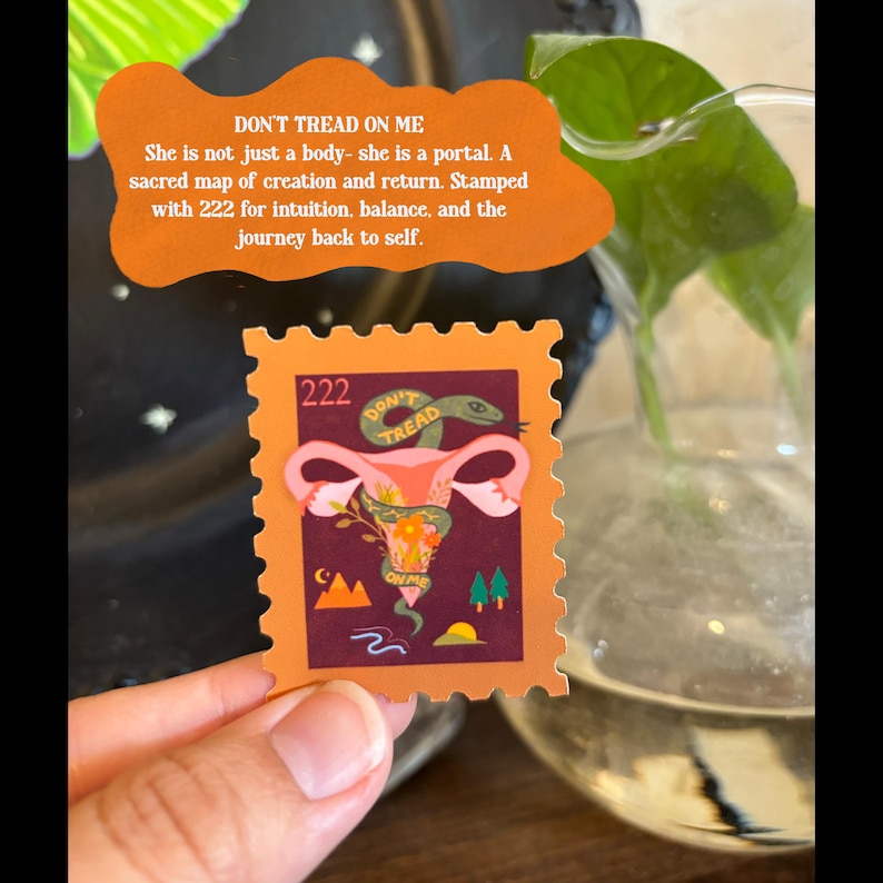 May include: A square sticker with an orange border features a stylized illustration of a uterus with a snake and floral elements. The text "DON'T TREAD" and "222" are visible. The sticker is held by a hand.