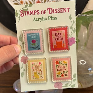 以下が含まれることがあります： 切手デザインのアクリルピン4個セット。ピンには「Abolish ICE」、「Eat the Rich」、「Fuck the Police」、「Fuck Fascism」などのフレーズが書かれています。各ピンは異なる配色とデザインで、花のアクセントが付いています。