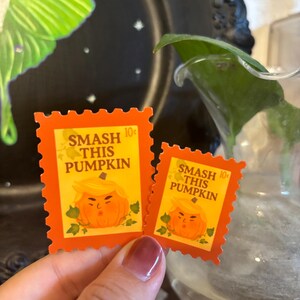 May include: Two orange postage stamps with a pumpkin design and the text "SMASH THIS PUMPKIN". The stamps have a 10&cent; value and are decorated with green leaves. The stamps are a Halloween-themed item.