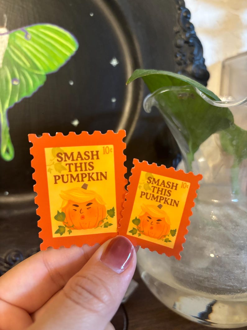 May include: Two orange postage stamps with a pumpkin design and the text "SMASH THIS PUMPKIN". The stamps have a 10&cent; value and are decorated with green leaves. The stamps are a Halloween-themed item.
