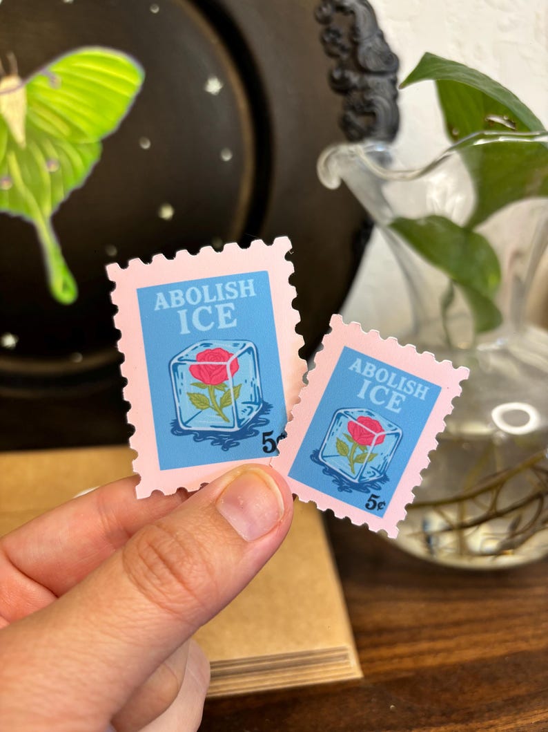 a stamp shaped sticker featuring a melting ice cube with a rose inside. text reads “abolish ice.”