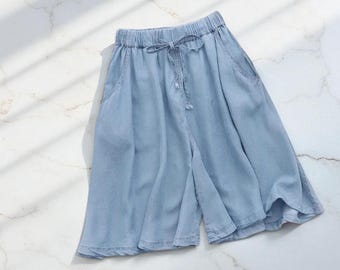 May include: Light blue culottes with an elastic waistband and drawstring. The shorts have two side pockets and a wide leg design. The fabric appears to be a lightweight denim or similar material.