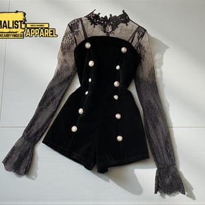 May include: Black velvet romper with gold buttons and sheer lace sleeves. The outfit features a high neckline and a shorts-style bottom. The sleeves have a gradient effect, transitioning from dark to light. The text "MINIMALIST APPAREL" is in the upper left corner.