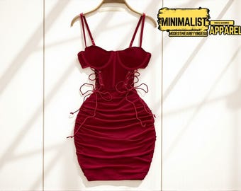 May include: A burgundy mini dress with spaghetti straps and a corset-style bodice. The dress features a ruched skirt and lace-up detailing. The words "MINIMALIST APPAREL" are in a yellow rectangle.