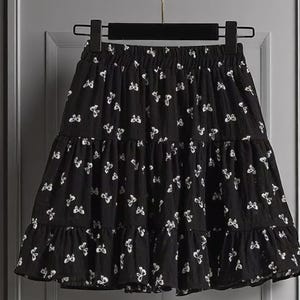 May include: Black tiered skirt with white butterfly pattern. The skirt is hanging on a black hanger. The skirt has an elastic waistband and a ruffled hem. The skirt is made of a lightweight fabric.
