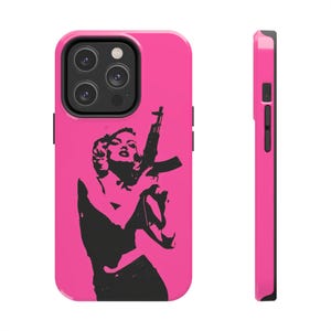 May include: A pink phone case with a black silhouette of a person holding a rifle. The phone case has a black camera lens cutout.