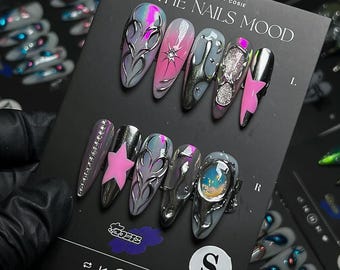May include: A set of long, almond-shaped artificial nails with various designs. The nails feature silver, pink, and gray colors, with embellishments like stars, rhinestones, and abstract patterns. The card reads "IN THE NAILS MOOD".