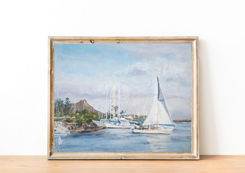 May include: A framed painting of a harbor scene with sailboats in the water. The sky is blue with white clouds. There are trees and a mountain in the background.