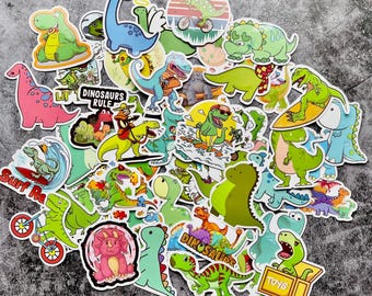May include: A collection of colorful dinosaur stickers in various shapes and sizes. The stickers feature cartoon dinosaurs in shades of green, blue, pink, and yellow. Some stickers have text, including "Dinosaurs Rule" and "Toys".