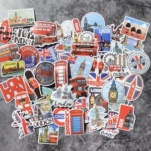 Può includere: Una collezione di adesivi a tema Londra con monumenti iconici come autobus rossi a due piani, il Big Ben e cabine telefoniche. Gli adesivi sono di varie forme e dimensioni, con testi come "London" e "England".