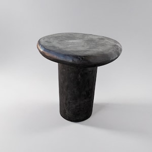 Op de afbeelding: Een ronde, paddenstoelvormige bijzettafel in zwart met een glad, licht onregelmatig blad en een cilindrische basis.