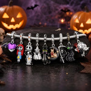 May include: A silver charm bracelet featuring nine Halloween-themed dangling charms, including a purple heart with bat wings, a female character with red hair, a skeleton figure with a coffin, a ghost, a black cat, a cat on a moon, a grim reaper, a black cat with green eyes, and a devil character.