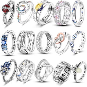 Peut inclure: Une collection de quatorze bagues argentées présentant divers motifs, notamment une coccinelle, des symboles célestes de soleil et de lune, des fleurs, des pierres bleues, des symboles infinis, des yeux protecteurs, des mains hamsa et des textes gravés.