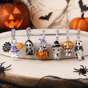 Könnte beinhalten: Ein silbernes Charm-Armband mit sechs Halloween-Anhängern: ein Geist mit lila Hut und Kürbis, ein Sensenmann, eine Hexe auf einem Kürbis, eine Mumie mit Hexenhut, eine Figur mit Kürbiskopf und ein Skelett, das einen Sarg hält.